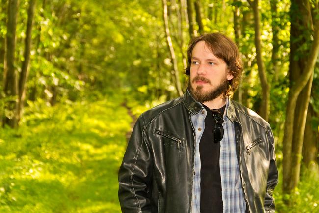 Modischer Mann mit Lederjacke im Wald